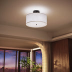  Side view shows linen drum shade, matte black metal base, and white diffuser panel with center finial