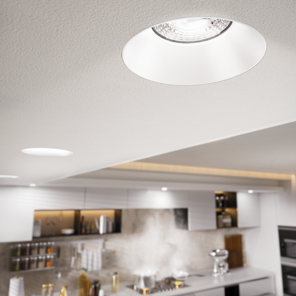Trimless recessed downlight installed flush in a ceiling over a kitchen, deep reflector and lens visible