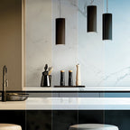 Black cylinder pendants over kitchen work surface