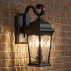 Bronze S-arm wall lantern illuminated against brick