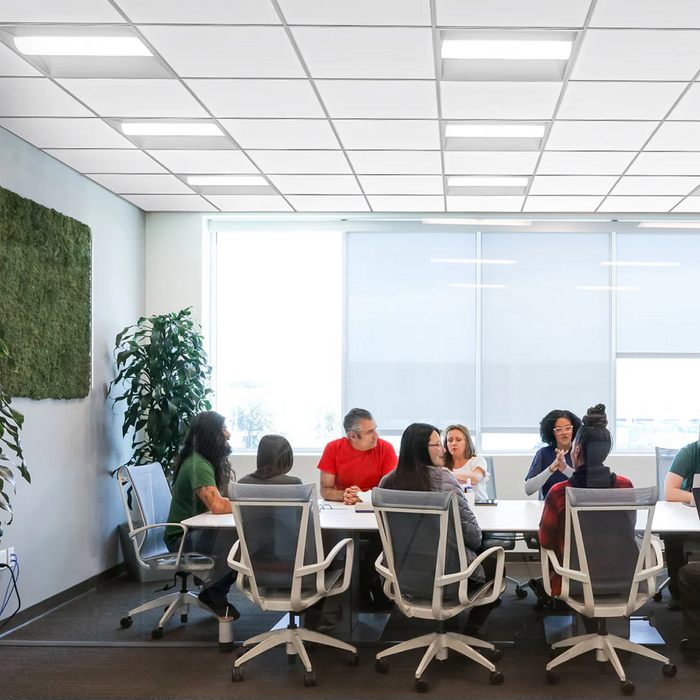 Group of people sitting around a table in a modern office setting with large windows.