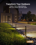 Row of slim black rectangular low-voltage LED path lights cast a warm 3000K yellowish glow on a concrete pathway to a house