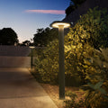 Garden lamp post illuminating a pathway at dusk with greenery around.