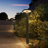 Garden lamp post illuminating a pathway at dusk with greenery around.