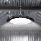 Lit UFO high bay suspended by chain under a corrugated metal ceiling, casting bright even light below.