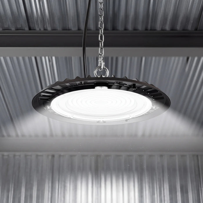 Lit UFO high bay suspended by chain under a corrugated metal ceiling, casting bright even light below.