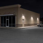 Bronze LED security wall packs with photocell lighting a retail store's side wall, walkway and parking lot at night