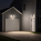 Bronze LED security wall packs with photocell lighting a house's garage door, side door and driveway at night